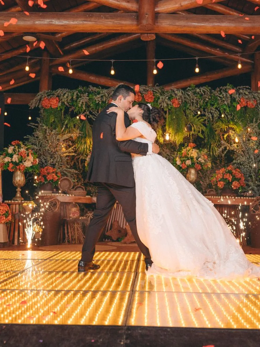 Casal dançando em pista iluminada durante recepção de casamento