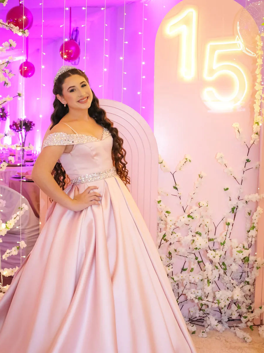 Debutante de vestido rosa ao lado do letreiro de neon com o número 15